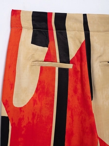 Detail of high-waisted printed trousers with red and black abstract geometric pattern