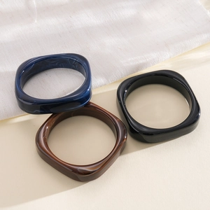 Detailed close-up of chunky square resin bangles set with marbled blue and brown patterns.