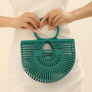 Detail of green semi-circular woven bamboo handbag with round handle on a white dress