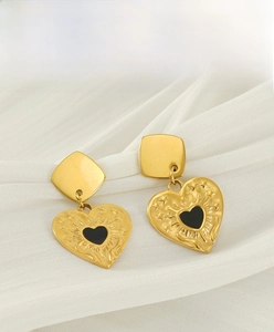 Vue détaillée de boucles d'oreilles cœur dorées 18K et émail noir sur fond de soie