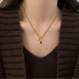 Close-up of 18K gold plated gourd necklace with tiger eye stone and crystals on a sweater