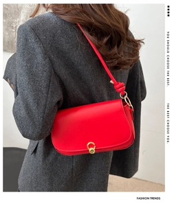 Model view of a minimalist red saddle bag with gold buckle on grey oversized blazer