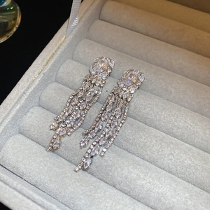Macro view of long silver tassel earrings with large oval cubic zirconia in a jewelry box