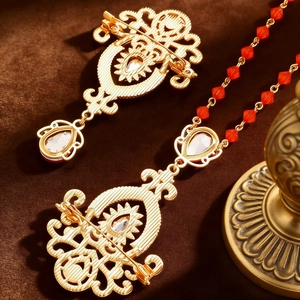 Close-up of vintage baroque brooch with red beads and clear crystals on gold alloy
