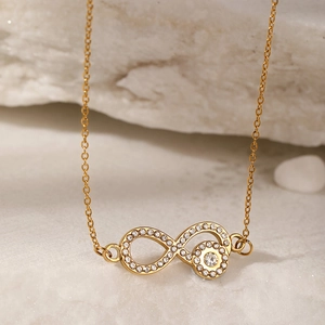 Macro shot of gold infinity pendant with pavé set cubic zirconia on white stone