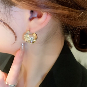 Détail d'une boucle d'oreille dorée en C avec cristaux micro-pavés et perle blanche