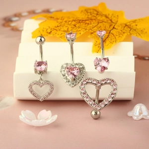 Pink heart zircon belly rings set in silver metal displayed on a warm autumn background