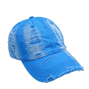 Close-up of distressed blue cotton denim baseball cap with vintage frayed hole details
