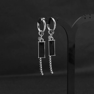 Detail of silver drop earrings with black rectangular gemstone and fringe chain tassel