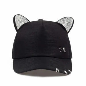 Detail of rhinestone cat ears and metal M badge on a black stylish baseball cap