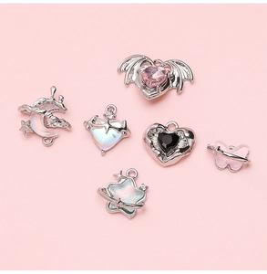 Detailed view of silver heart, moon and butterfly charms with colorful glass gems