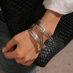 Close-up of polished silver multi-layer geometric wire cuff bracelet worn by a model