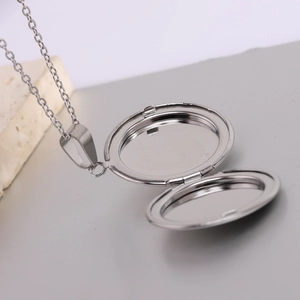 Detailed close-up of an open round silver locket necklace with smooth polished metal finish