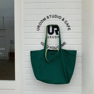 Detail of dark green canvas tote bag with grid lining and merciparis woven label