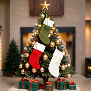 Three knitted Christmas stockings with pom-poms hanging on a festive decorated tree
