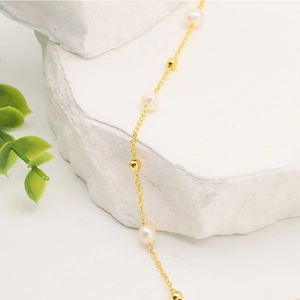 Macro detail of natural freshwater pearl necklace with 18k gold plated chain and beads