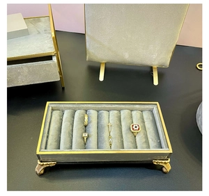 Detail view of golden metal frame jewelry tray with gray velvet and relief feet