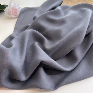 Macro shot of grey linen scarf with soft pleated texture and elegant rose detail