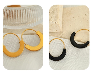 Detailed close-up of French style U-shaped enamel hoop earrings in gold and black metal