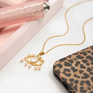 Detail of gold evil eye necklace with white zircon and pearls on velvet box