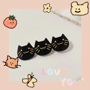 Detail shot of black acetate hair clip with three golden-detailed cartoon cat heads