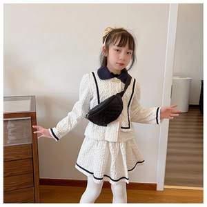 Detail of a white textured tweed two-piece girls' set with a black quilted waist bag
