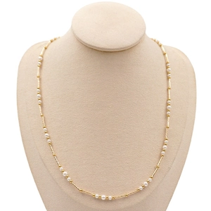 French vintage style long pearl necklace with golden metal accents on a beige display stand