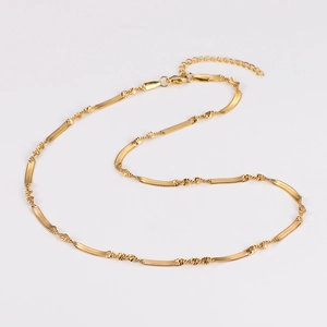 Detail of gold snake bone chain necklace featuring small bead accents and adjustable lobster clasp