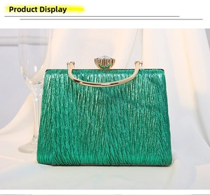 Detail of emerald green pleated evening bag with gold metal handle and crystal clasp