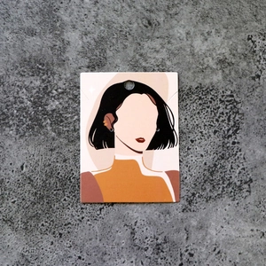 Macro detail of jewelry display card with artistic female illustration on gray background