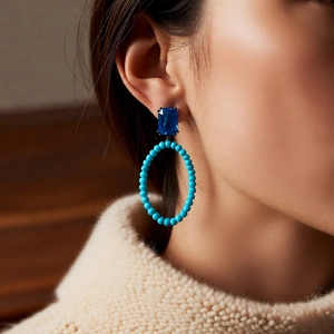 Detail of oval drop earring with a blue gemstone and turquoise beads on model