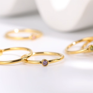Macro detail of a minimalist gold ring featuring a bezel-set purple birthstone gemstone