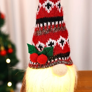 Makroaufnahme von leuchtendem Weihnachtszwerg mit roter Strickmütze und warmem LED-Licht