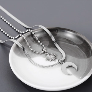 Detail of silver double-layered snake chain with moon and sun star pendants