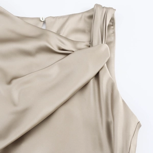 Détail de la robe en satin champagne avec nœud à l'épaule et fermeture à bouton