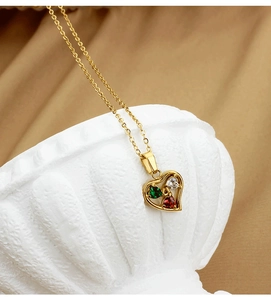 Detailed close-up of heart pendant with green, white, and red crystals on a gold chain