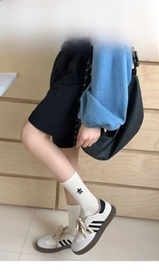 Detail of white cotton mid-tube socks with black star patterns and letter embroidery