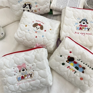 Close-up of quilted heart fabric and cute cartoon dog embroidery on a beige cosmetic bag