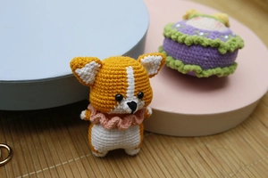 Close-up of handmade crochet corgi puppy with pink scarf and detailed yarn texture