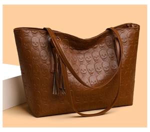 Detailed view of embossed skull pattern and leather tassel on the brown tote bag