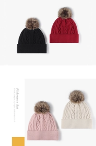 Detail of four knit beanies featuring chunky cable patterns and faux fur pom-poms
