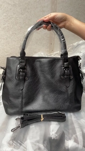 Detail of black pebbled faux leather handbag with silver hardware and adjustable strap