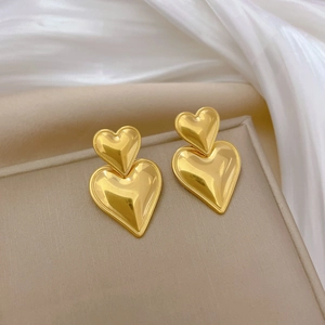 Close-up of double heart titanium steel earrings in gold finish on silk background