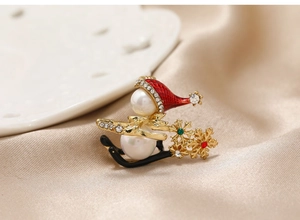 Macro detail of Christmas snowman sleigh brooch with gold plating and pearl accents