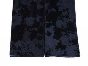 Dettaglio di un abito in velluto tie-dye marmorizzato scuro con spacco laterale e trama