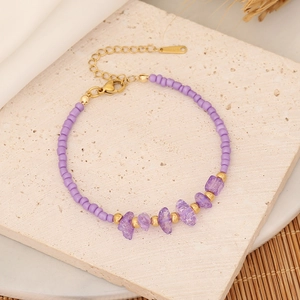 Bohemian purple natural stone bead bracelet with gold chain on a textured marble base