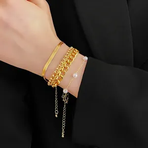 Four-piece gold layered bracelet set with pearls and snake chain on model wrist