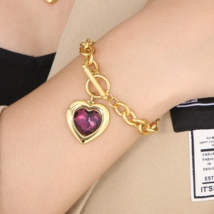 Detail of gold chain bracelet with purple crystal heart pendant and toggle clasp