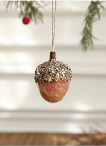 Macro shot of glittery pinecone acorn felt ornament hanging on a festive Christmas tree branch