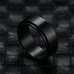 Macro detail of black matte stainless steel spinner ring on dark leather background